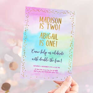 May include: A colorful invitation with gold glitter accents. The text reads "Madison is Two! Abigail is One! Come help us celebrate with double the fun! Saturday November 15th 6:00 PM 125 West 8th Street New York, NY 10003 RSVP by Nov 5th 97628265 call or text"