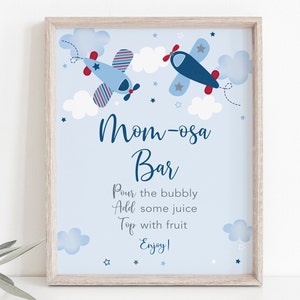 May include: A blue and white printable sign with a Mom-osa Bar title and instructions for making a mimosa. The sign features two cartoon airplanes flying in a blue sky with white clouds and stars.