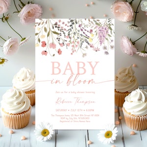 Puede incluir: Una invitación de baby shower blanca con ilustraciones florales rosas y el texto "BABY in bloom". La invitación incluye el nombre "Rebecca Thompson", la fecha "SATURDAY JULY 15TH", la hora "6:00PM", la dirección "The Thompson home, 125 West 18th Street, NY 10024", la información RSVP "RSVP by July 5th. 917.628.2455", y la información de registro "Registered at Store Names Here".