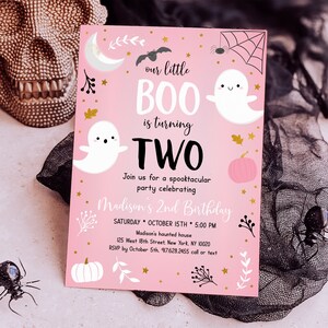 May include: Pink and white Halloween birthday invitation with a ghost and a bat. The text reads "our little BOO is turning TWO. Join us for a spooktacular party celebrating Madison's 2nd Birthday. SATURDAY OCTOBER 15TH 5:00 PM Madison's haunted house 125 West 18th Street, New York, NY 10020 RSVP by October 5th, 917.628.2455 call or text"