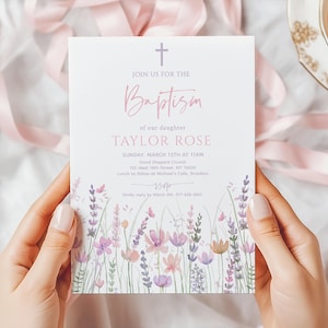 Może przedstawiać: Karta zaproszenia na chrzest trzymana w dłoniach. Karta zawiera krzyż u góry z napisem „Join us for the Baptism of our daughter TAYLOR ROSE”. Kwiatowy wzór akwarelowy w kolorze różowym i fioletowym. Karta zawiera szczegóły wydarzenia.