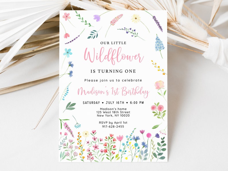 Puede incluir: Una invitaci&oacute;n de primer cumplea&ntilde;os con tem&aacute;tica floral para una ni&ntilde;a llamada Madison. La invitaci&oacute;n presenta una ilustraci&oacute;n de acuarela de flores silvestres coloridas y el texto "Nuestra peque&ntilde;a Flor silvestre cumple un a&ntilde;o". Incluye la fecha, la hora y el lugar de la fiesta, as&iacute; como una fecha l&iacute;mite para confirmar asistencia.