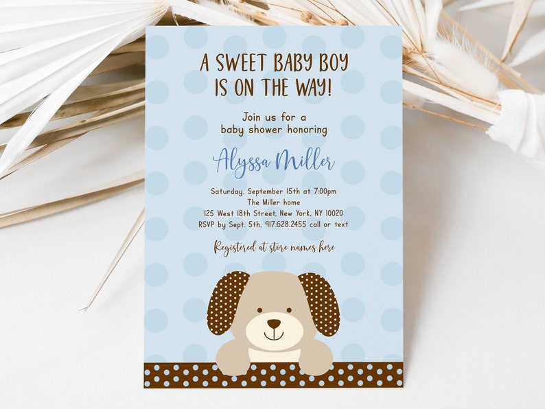 May include: A blue baby shower invitation with white polka dots. The invitation features a cartoon brown puppy with brown ears and a brown nose. The text on the invitation reads "A Sweet Baby Boy Is On The Way!" and includes the name "Alyssa Miller".