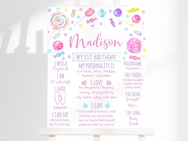 K&ouml;nnte beinhalten: Ein rosa-blaues Schild zum ersten Geburtstag mit Bonbon-Illustrationen. Das Schild tr&auml;gt den Namen "Madison" und enth&auml;lt Details &uuml;ber das Alter, das Gewicht, die Gr&ouml;&szlig;e, die Lieblingsessen und die Aktivit&auml;ten des Kindes.