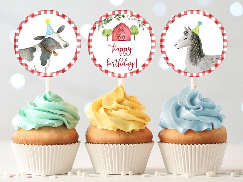May include: Three cupcakes decorated with red and white checkered circles. The circles feature a cow, a horse, and a red barn with the text "happy birthday!"