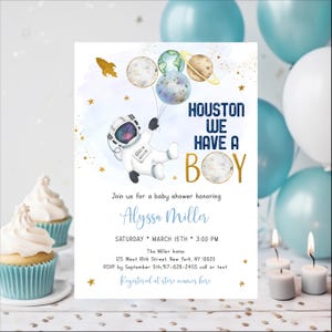 May include: A baby shower invitation with a blue and gold color scheme. The invitation features an astronaut holding balloons shaped like planets. The text on the invitation reads "Houston, we have a boy".