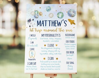 May include: A blue and gold printable sign with a space theme for a child's first birthday. The sign includes the name "Matthew's" and the text "1st trip around the sun". It also includes details about the child, such as their weight, height, and favorite things.