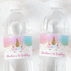 Può includere: Due bottiglie d'acqua in plastica trasparente con etichette che mostrano un unicorno con un corno dorato e glitter rosa e blu. Le etichette riportano anche la scritta "Madison's 1st Birthday".