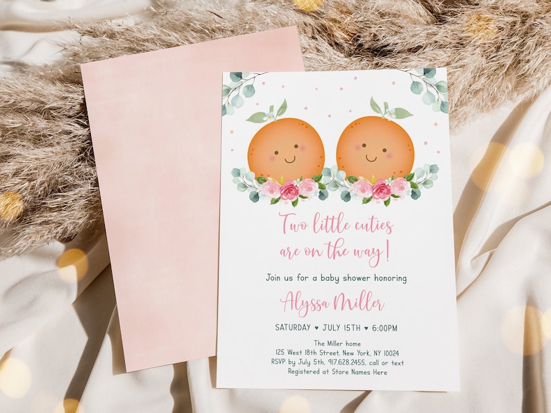 Puede incluir: Una invitaci&oacute;n a un baby shower con un dise&ntilde;o floral rosa y blanco. Dos frutas naranjas con caras sonrientes est&aacute;n en la parte superior de la invitaci&oacute;n. El texto dice "&iexcl;Dos peque&ntilde;os encantos est&aacute;n en camino!" y "&Uacute;nete a nosotros para un baby shower en honor a Alyssa Miller".
