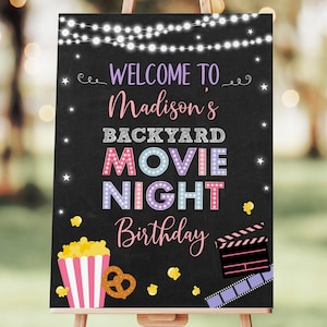 May include: A black chalkboard sign with white string lights, stars, and popcorn. The sign says "Welcome to Madison's Backyard Movie Night Birthday".