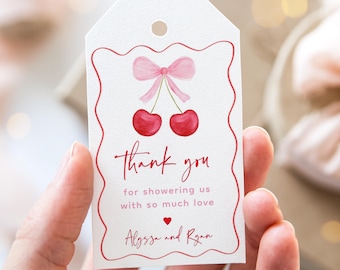 May include: White thank you tag with a red border and a pink bow with two red cherries. The text reads "Thank you for showering us with so much love Alyssa and Ryan".