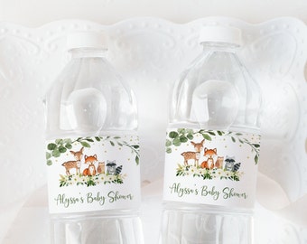 May include: Two clear plastic water bottles with labels featuring a woodland animal theme. The labels have a green leafy border with a deer, fox, cat, and raccoon. The text on the labels reads "Alyssa's Baby Shower".