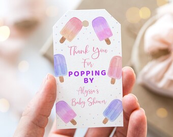 May include: A white gift tag with watercolor popsicle illustrations in pink, purple, and orange. The tag reads "Thank You For Popping By Alyssa's Baby Shower" in pink and purple script. Small purple dots are scattered around the edges.