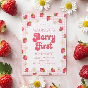 Puede incluir: Una invitaci&oacute;n de fiesta con estampado de vichy rosa y blanco con tem&aacute;tica de fresa. La invitaci&oacute;n dice "Join us for Madison's Berry First Birthday" con un coraz&oacute;n y la fecha y hora de la fiesta. La invitaci&oacute;n est&aacute; rodeada de fresas y margaritas blancas.
