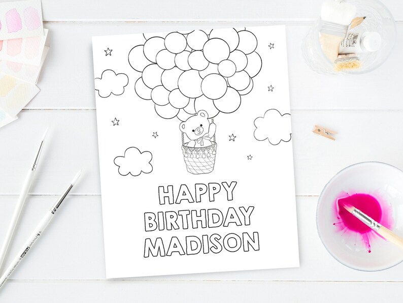 May include: A black and white coloring page featuring a teddy bear in a hot air balloon with the text "Happy Birthday Madison".