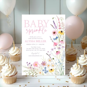 May include: A baby sprinkle invitation with the words "BABY sprinkle" in pink script. The invitation features watercolor floral illustrations in pink, purple, yellow, and blue. Cupcakes with candles and pink and white balloons surround the invitation.