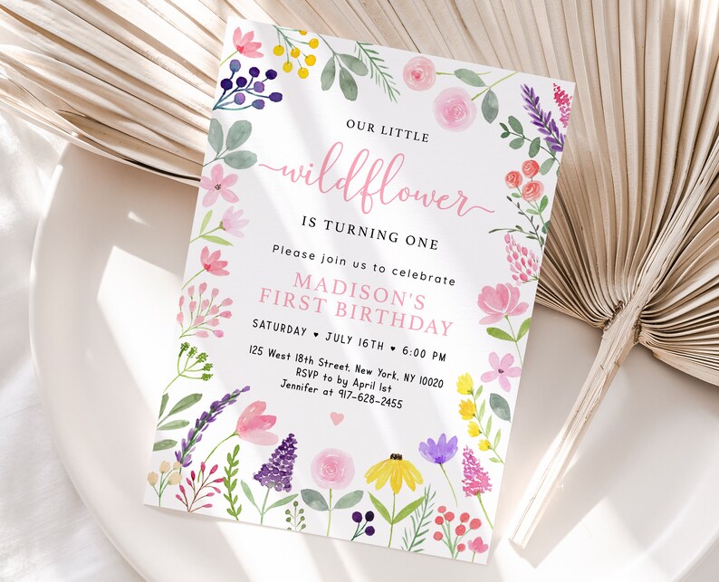 May include: A floral-themed first birthday invitation for a girl named Madison. The invitation features a watercolor illustration of pink, purple, and yellow flowers with green leaves. The text reads "Our Little Wildflower is Turning One. Please join us to celebrate Madison's First Birthday. Saturday, July 16th, 6:00 PM. 125 West 18th Street, New York, NY 10020. RSVP to by April 1st. Jennifer at 917-628-2455."