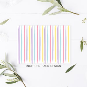 May include: A white card with pastel pink, yellow, blue, and purple stripes. The text "INCLUDES BACK DESIGN" is printed at the bottom of the card.
