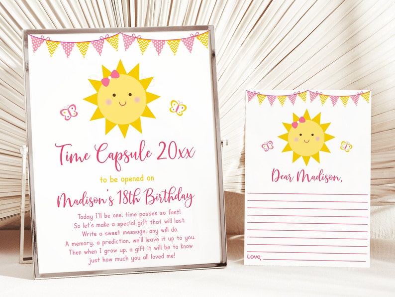 May include: A pink and yellow time capsule card with a smiling sun illustration and butterflies. The card says "Time Capsule 20xx to be opened on Madison's 18th Birthday". The text below reads "Today I'll be one, time passes so fast! So let's make a special gift that will last. Write a sweet message, any will do. A memory, a prediction, we'll leave it up to you. Then when I grow up, a gift it will be to know just how much you all loved me!"