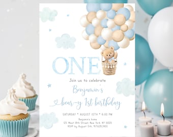 May include: A blue and white invitation card with a teddy bear in a hot air balloon made of blue and beige balloons. The card says "ONE" and "Join us to celebrate Benjamin's bear-y 1st birthday". The card also includes the date, time, and location of the party.