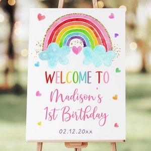 K&ouml;nnte beinhalten: Willkommen zum 1. Geburtstag von Madison Schild mit einem Regenbogen, Wolken und Herzen. Der Regenbogen ist in Aquarell gemalt und mit goldenem Glitzer verziert. Das Schild hat einen wei&szlig;en Hintergrund.
