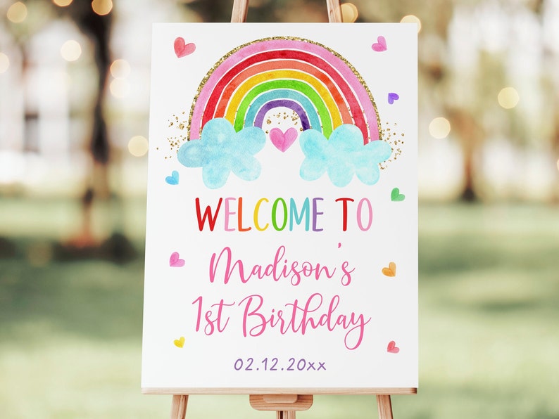 K&ouml;nnte beinhalten: Willkommen zum 1. Geburtstag von Madison Schild mit einem Regenbogen, Wolken und Herzen. Der Regenbogen ist in Aquarell gemalt und mit goldenem Glitzer verziert. Das Schild hat einen wei&szlig;en Hintergrund.