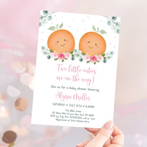 Puede incluir: Una invitaci&oacute;n a una fiesta de bienvenida al beb&eacute; de color rosa y blanco con un dise&ntilde;o floral y dos ilustraciones naranjas con caras sonrientes. El texto dice "&iexcl;Dos peque&ntilde;os encantos est&aacute;n en camino!" e incluye el nombre "Alyssa Miller", la fecha "S&aacute;bado 15 de julio", la hora "6:00 PM", la ubicaci&oacute;n "The Miller home", la direcci&oacute;n "125 West 18th Street, New York, NY 10024", la informaci&oacute;n de RSVP "RSVP antes del 5 de julio, 97628 2455, llama o env&iacute;a un mensaje de texto", y la informaci&oacute;n de registro "Registrado en Store Names Here".