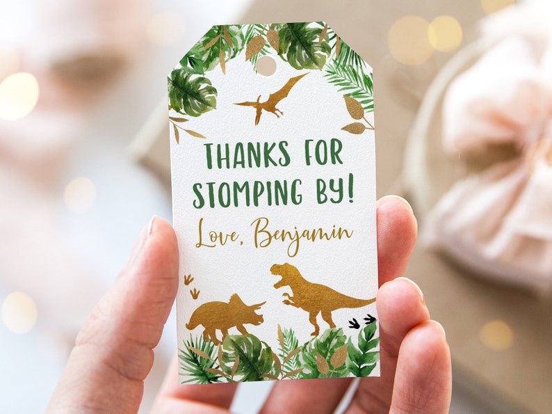 May include: A white thank you tag with green and gold foliage and dinosaur silhouettes. The text reads "Thanks for stomping by! Love, Benjamin".