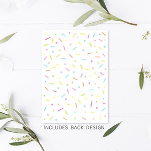 May include: A white card with a colorful confetti pattern. The card says "Includes Back Design" at the bottom.