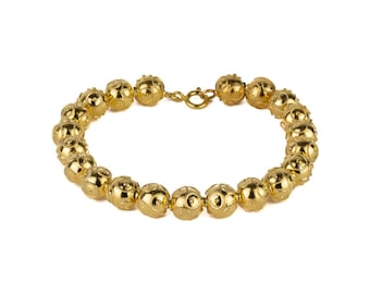 May include: A gold necklace with a chain of round, textured beads.