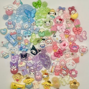 May include: A collection of colorful resin charms featuring various cute characters, including Hello Kitty, a bear, a butterfly, and a popsicle. The charms are perfect for adding a touch of whimsy to jewelry, crafts, and other projects.