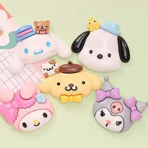 May include: A collection of five colorful character-shaped decorative items. The characters include a white dog with black ears, a yellow dog with a brown hat, a pink cat with a bow, a white bunny with a blue hat, and a gray cat with a skull.