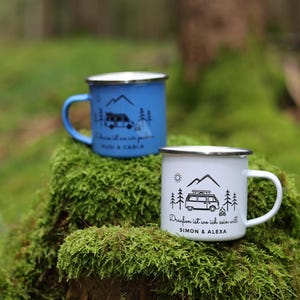 May include: Two enamel camping mugs with a camper van design. The blue mug says "Draufan ist wo ich sein will Rudi & Carla". The white mug says "Draufan ist wo ich sein will Simon & Alexa".