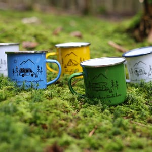 May include: Five enamel camping mugs with different designs and colours. The mugs feature a camper van and trees. The text on the mugs reads "Choose it, love it, pack it, drive it, camp it" and "Adventure starts here".