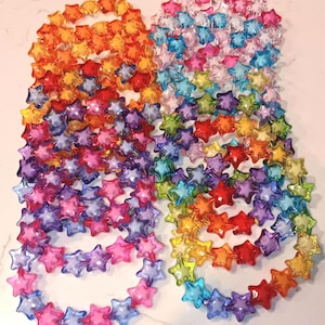 May include: A collection of colorful star-shaped bracelets made of plastic. The bracelets are arranged in a rainbow pattern, with each bracelet featuring a different color.