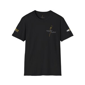 May include: Black t-shirt with gold and white graphics. The front features the text "TINY LOU" with a gold line drawing. The left sleeve has "SOUND ENGINEERS" in gold. The right sleeve has a white graphic. A crew neck tee.