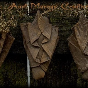 May include: Three brown fabric wall hangings with a rustic, vintage look. The hangings are made of folded fabric and have a textured, worn appearance.