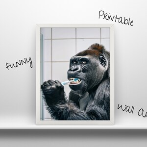 May include: A black and white photo of a gorilla brushing its teeth with a toothbrush. The gorilla is looking at the camera and has a serious expression on its face. The photo is framed in a white frame.