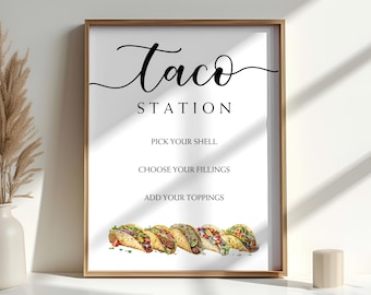 May include: A framed print with the words "Taco Station" in elegant script. Below, it lists "Pick Your Shell," "Choose Your Fillings," and "Add Your Toppings." A watercolor illustration of tacos is at the bottom. The frame is gold.