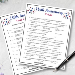Pode incluir: Duas folhas de trivia impressas para o 250&ordm; anivers&aacute;rio, com perguntas sobre a Declara&ccedil;&atilde;o de Independ&ecirc;ncia e a hist&oacute;ria americana. As folhas s&atilde;o brancas com decora&ccedil;&otilde;es de estrelas vermelhas, brancas e azuis. Uma caneta preta repousa sobre as folhas.