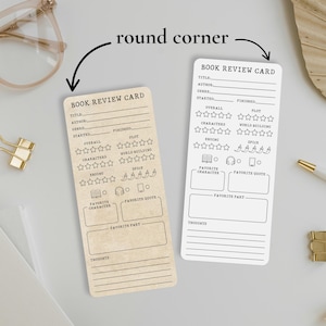 May include: Two rectangular book review cards with rounded corners. One card is tan, the other is white. Both cards have the text "BOOK REVIEW CARD" at the top, with sections for title, author, and plot. There are also sections for rating the book.