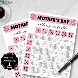 May include: Two printable Mother's Day games with pink dice and floral accents. The text "Mother's Day rolling in faith" is at the top. A black pen and a cup of coffee are also visible. An "Instant Download" graphic is in the lower left.