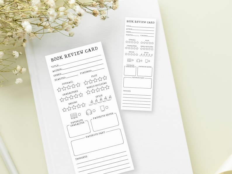 May include: Two white book review cards with black text and outlines. The cards include sections for title, author, genre, and ratings for plot, characters, and spice. One card is a bookmark shape. The text "BOOK REVIEW CARD" is at the top.