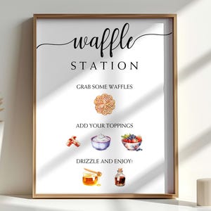 Peut inclure: Une affiche encadrée avec les mots "waffle STATION" en écriture noire. L'affiche comprend des illustrations à l'aquarelle de gaufres, de garnitures et de condiments. Le texte se lit comme suit : "Prenez des gaufres, ajoutez vos garnitures, arrosez et savourez !"