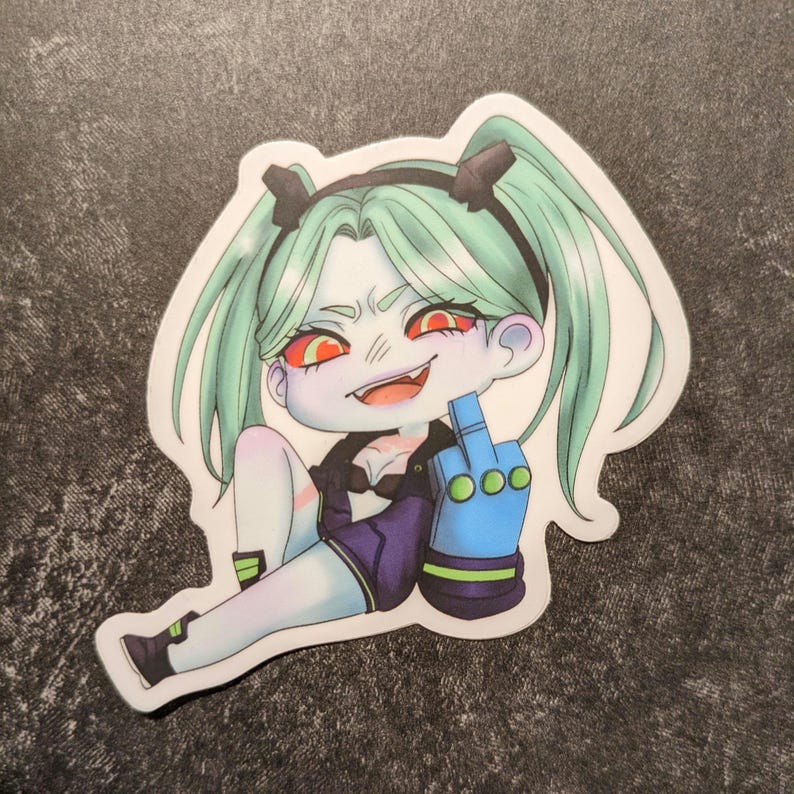 May include: A sticker featuring a cartoon character with green hair in pigtails, red eyes, and a mischievous grin. The character is giving the middle finger with a blue hand. The character is wearing a black top and purple shorts.