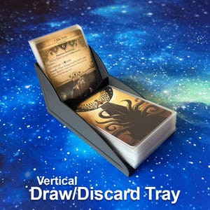 May include: A dark gray plastic card holder featuring two tiered sections for a draw and discard pile. The upper section holds a single card with the text Julia Stern, while the lower section holds a stack of cards with a tentacle illustration.