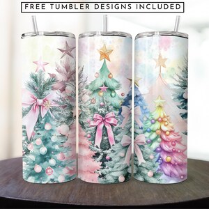May include: Three stainless steel tumblers featuring a Christmas tree design. The tumblers are decorated with watercolour-style illustrations of Christmas trees in pink, green, and rainbow colours. The trees are adorned with baubles and bows.