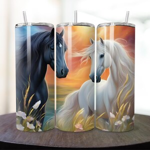 May include: Three stainless steel tumblers with a black horse and a white horse on a sunset background. The tumblers are all the same size and have a straw.