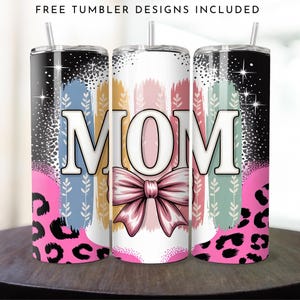 Peut inclure: Trois gobelets en acier inoxydable avec couvercles et pailles. Chaque gobelet présente le mot "MOM" en grandes lettres blanches, un nœud rose et un fond coloré. Le design comprend un imprimé léopard rose et le texte "FREE TUMBLER DESIGNS INCLUDED".