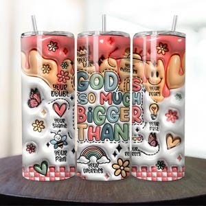 May include: A white tumbler with a pink, white, and yellow dripping design. The tumbler has a colorful graphic that says "God is so much bigger than your doubt, your hurt, your shame, your pain, your worries, your mistakes, your fears, your regrets, your past".